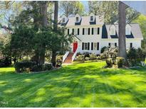 Charming two-story home with a manicured lawn, lush landscaping, and a welcoming red front door at 7721 Sutcliffe Dr, Raleigh, NC 27613