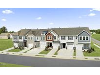 Beautiful townhomes boast attached garages, multiple stories, and landscaped lawns under a partly cloudy blue sky at 90 Hyacinth Ln # 90, Angier, NC 27501