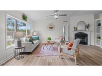 Cozy living room featuring a fireplace, wood floors, and abundant natural light from a large window at 92 Papoose Trl, Lillington, NC 27546