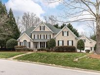 Elegant, two-story brick home boasts a lush lawn and mature landscaping for enhanced curb appeal at 101 Hedwig Ct, Cary, NC 27518