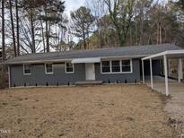 Charming single-story home featuring a gray brick facade, covered carport, and well-manicured front yard at 1128 Horseshoe Rd, Durham, NC 27703