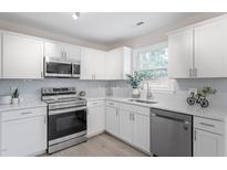 Bright kitchen features stainless steel appliances, white cabinets, and light backsplash at 1206 Dubose St, Garner, NC 27529