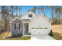 Charming single Gathering home with stone accents, lush landscaping, and an attached two-car garage at 121 Sacred Fire Rd, Louisburg, NC 27549