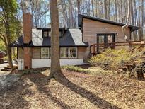 View of the home's exterior, featuring wood siding, a brick chimney, and a sloped roof at 1269 Manns Chapel Rd, Pittsboro, NC 27312