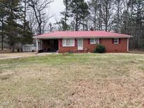 Charming red brick home with red roof and a spacious front yard surrounded by mature trees at 16 Marsh Mciver Rd, Bear Creek, NC 27207