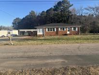 Charming brick home with blue shutters and a covered porch, surrounded by a lush, green lawn at 300 Grove St, Oxford, NC 27565