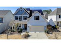 Charming two-story home featuring a well-maintained lawn, a two-car garage, and modern solar panels on the roof at 305 Chestnut Oaks Pl, Durham, NC 27704