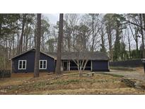 Charming navy home boasts mature trees, brick foundation, and a stone bench in the front yard at 3916 Allen W St, Raleigh, NC 27603