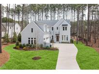 A charming, two-story grey home features a manicured lawn and a long driveway at 49 Bonterra Way, Chapel Hill, NC 27516