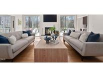 Bright living room features a fireplace, hardwood floors, and access to an outdoor deck through glass doors at 104 Hampshire Pl, Chapel Hill, NC 27516
