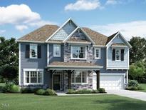 Charming two-story home featuring stone accents, a covered porch, and a two-car garage on a well-manicured lawn at 1385 Sparkling Lake Dr # 45, Apex, NC 27523