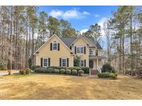 Charming yellow two-story home with black shutters and manicured landscaping surrounded by trees at 151 Bennett Pl, Clayton, NC 27527