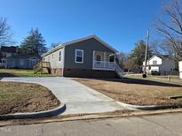 Charming gray home featuring a brick foundation and a freshly poured concrete driveway at 209 King St, Oxford, NC 27565