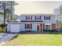 Charming two-story home with light blue siding, red shutters, and a well-manicured lawn, exuding classic curb appeal at 2513 Boothbay Ct, Raleigh, NC 27613