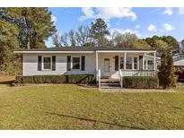 Charming single-story home featuring a well-maintained lawn and a welcoming front porch with decorative shrubbery at 4316 Old Faison Rd, Knightdale, NC 27545