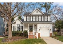 Charming two-story white home with black shutters, landscaped front yard, and attached garage on a sunny day at 5704 Edgebury Rd, Raleigh, NC 27613