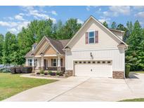 Traditional style home featuring a manicured lawn, two-car garage, and welcoming front porch at 70 Breadnut Dr, Smithfield, NC 27577