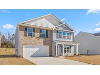 Charming two-story home with brick and light blue siding, complemented by dark shutters and an attached garage at 215 Leven Dr, Gibsonville, NC 27249