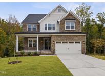 Beautiful two-story home featuring a stone facade, inviting front porch, and a two-car garage at 3154 Armeria Dr, Apex, NC 27502