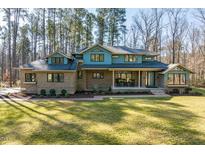 Two-story brick home with a blue accent wall, inviting front porch and a manicured lawn at 38 Kingbird Ln, Chapel Hill, NC 27517