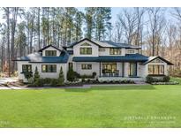 Stunning two-story home boasts a white painted brick exterior, black accents, and a lush green lawn at 38 Kingbird Ln, Chapel Hill, NC 27517
