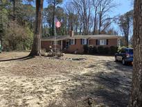 Charming single-story brick home with mature trees and an American flag in a spacious front yard at 431 S Harrison Ave, Cary, NC 27511