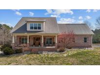 Charming brick home featuring a metal roof, covered front porch, and professionally landscaped yard at 4420 Bunton Swaim Rd, Liberty, NC 27298