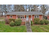 Charming brick home featuring a cozy front porch and well-manicured landscaping at 461 Camp Rd, Burlington, NC 27217