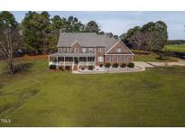 Charming brick home with a large porch and a well-manicured lawn, surrounded by mature trees at 6404 Pulley Town Rd, Wake Forest, NC 27587