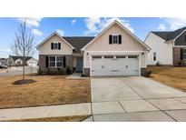 Charming one-story home with a two-car garage and a combination of stone and vertical siding at 82 Coble Farms Pl, Fuquay Varina, NC 27526