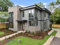 Modern home featuring a gray exterior with a brick accent, professionally landscaped lawn, and a welcoming front entrance at 2305 Turners Aly, Raleigh, NC 27607