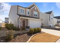 Charming two-story home showcasing a two-car garage, well-kept lawn, and attractive mixed siding and stone details at 917 Matterhorn Dr, Fuquay Varina, NC 27526