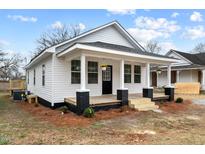 Charming single-story home with a welcoming front porch and freshly painted white siding at 1034 Maple St, Henderson, NC 27536