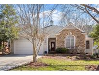Charming home featuring a two-car garage, stone accents, a well-manicured lawn, and mature trees at 107 Helmsdale Dr, Chapel Hill, NC 27517