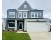 Charming two-story home with gray siding, stone accents, a two-car garage and a well-manicured lawn at 130 W Crescent Mills Blvd # Homesite 251, Wilson's Mills, NC 27520