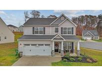 Charming two-story home with gray siding, black shutters, a two-car garage, and a cozy front porch at 1725 Langlais Dr, Graham, NC 27253