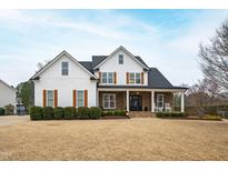 Beautiful two-story home with white siding, stone accents, black roof and inviting front porch at 222 Friesan Way, Rolesville, NC 27571