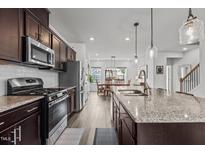 Beautiful kitchen featuring dark cabinets, stainless steel appliances, and a granite island flowing into the dining area at 5818 Humanity Ln, Raleigh, NC 27616
