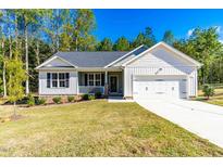 Charming home boasts a two-car garage, manicured lawn, and inviting front porch, perfect for relaxing outdoors at 61 Okra Ct, Selma, NC 27576