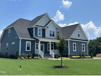 Charming two-story home featuring a manicured lawn, blue siding, and a welcoming front porch at 70 Prency Ln, Middlesex, NC 27557