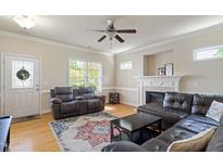 Bright living room featuring hardwood floors, a fireplace, and comfortable leather seating at 801 Myrtle Grove Ln, Apex, NC 27502