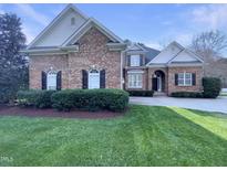 Charming brick home featuring black shutters, arched windows, a well-manicured lawn, and a circular driveway at 138 Parkdale Ln, Clayton, NC 27520