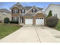Charming two-story home featuring a stone facade, two-car garage, and well-manicured lawn at 1756 Main Divide Dr, Wake Forest, NC 27587