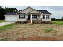 Charming single-Gathering home featuring a covered porch, attached garage, and beautifully manicured front yard at 186 N Movado Trl, Kenly, NC 27542
