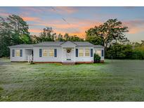 Charming single-story home with manicured front yard and inviting entrance at sunset at 201 Colonial Ave, Goldston, NC 27252