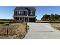 Two-story home with gray siding, a dark roof, and a paved driveway leading to an attached garage at 22 Wynd Crest Way, Benson, NC 27504
