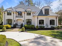 Stately white brick home featuring manicured landscaping and a circular driveway at 2710 Cambridge Rd, Raleigh, NC 27608