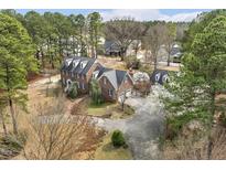 Stunning aerial view of a brick home featuring a circular driveway and well-manicured lawn surrounded by mature trees at 3715 Rawls Church Rd, Fuquay Varina, NC 27526
