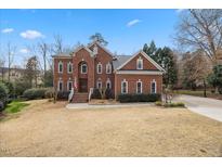 Beautiful two-story brick home with manicured lawn and inviting entrance with a basketball court in the driveway at 10801 Crosschurch Ln, Raleigh, NC 27614