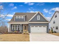 Charming two-story home with a two-car garage, a quaint front porch, and manicured landscaping at 112 Sire Ct, Holly Springs, NC 27540